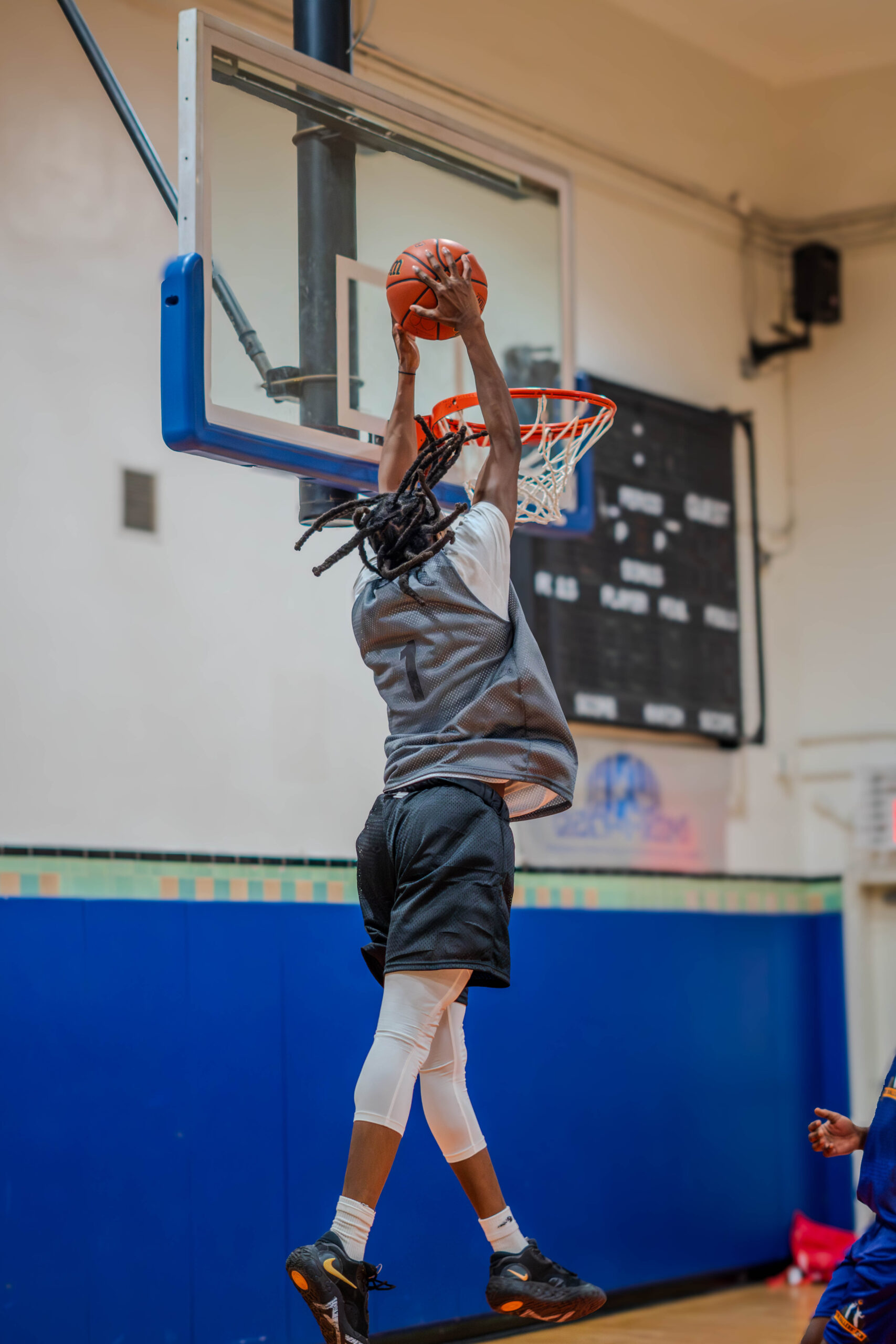 A basketball player driving towards the hoop, ready to score a layup as defenders try to block, capturing the intensity and determination of the game.